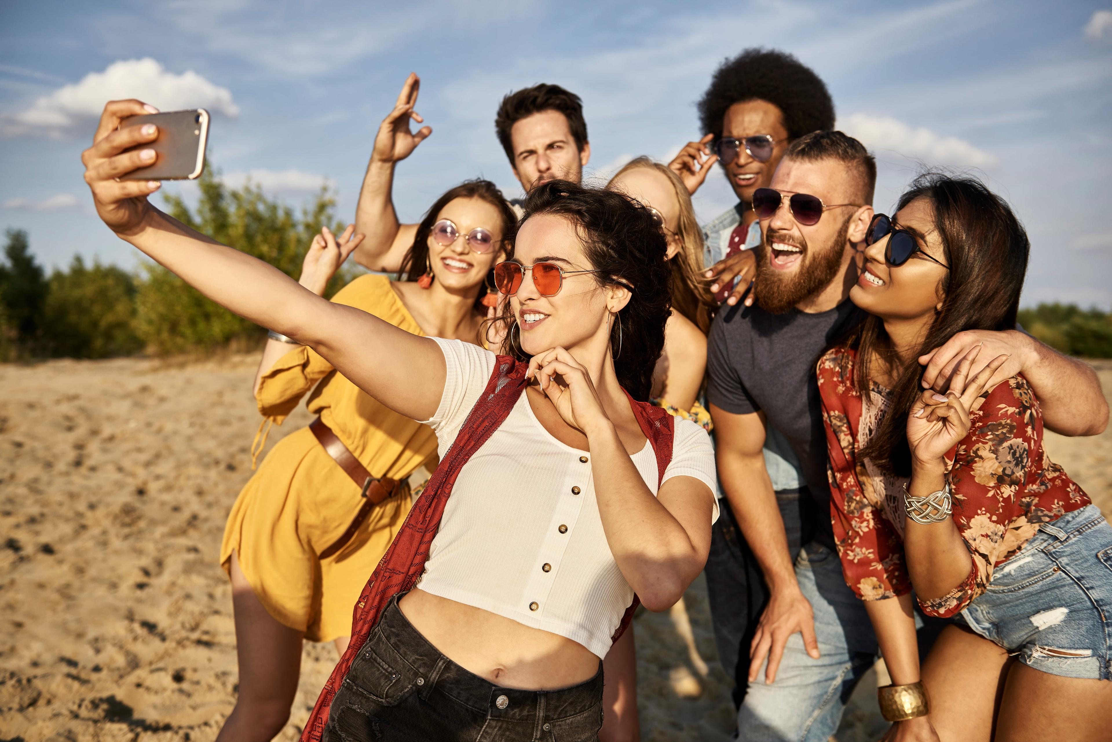 Group of happy travelers taking a selfie on the beach